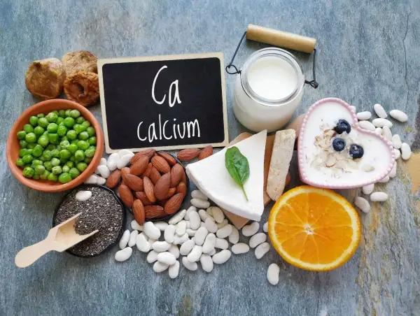 Assortiment d'aliments riches en calcium : lait, yaourt, fromage, amandes, haricots blancs, pois, figues séchées, graines de chia et orange.